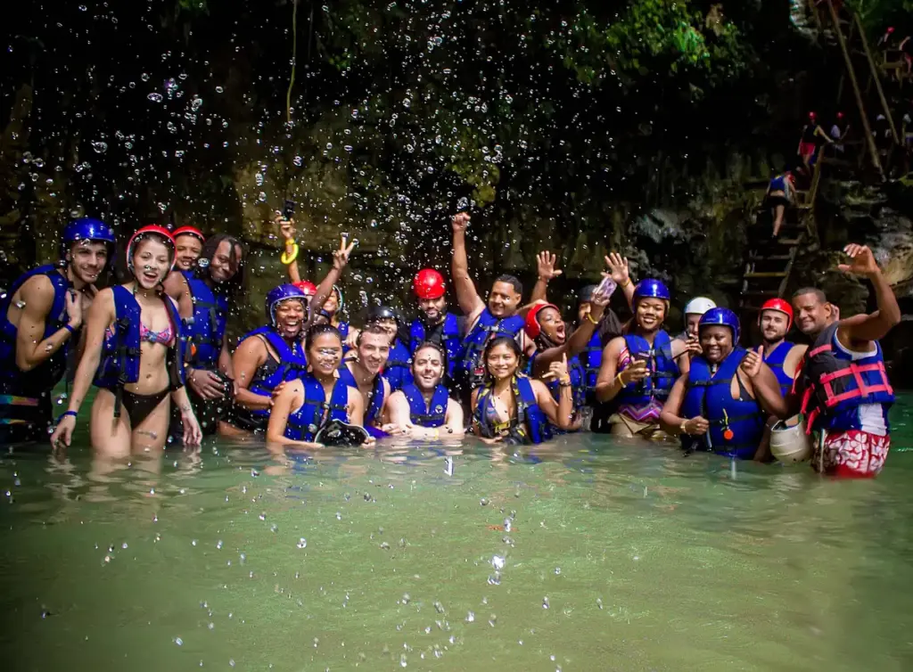 Grupo de visitantes con cascos y chalecos salvavidas dentro de una poza de los charcos de Damajagua