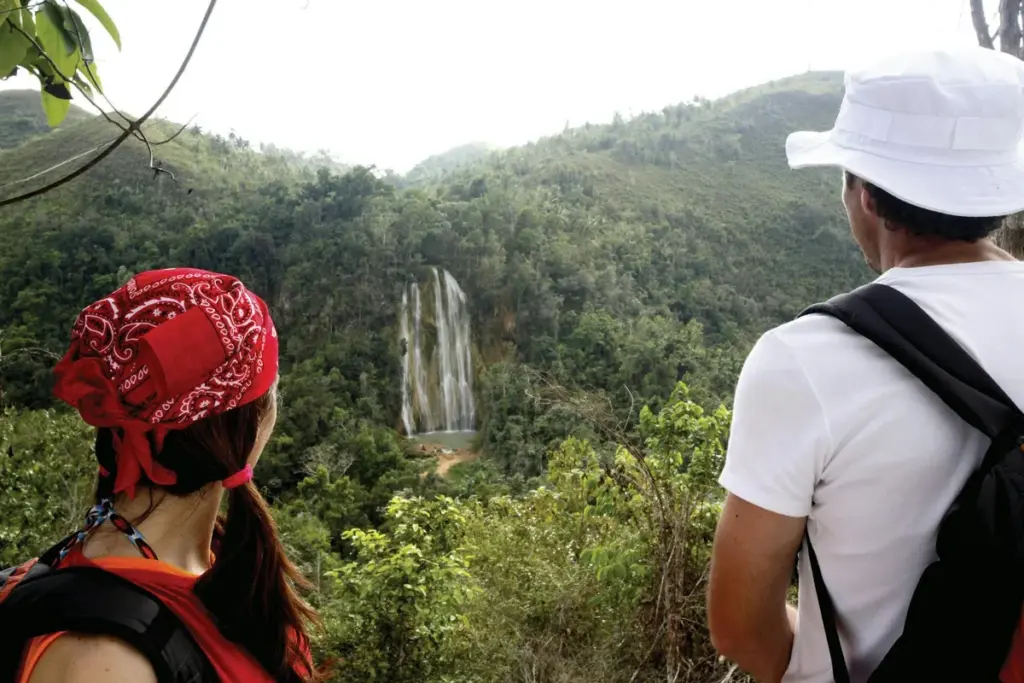 Dos caminantes con mochila observan desde un mirador el Salto El Limón entre la selva