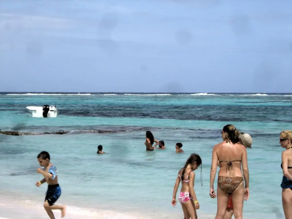 Familias bañándose en aguas tranquilas y turquesas frente a la playa de Club Med Punta Cana