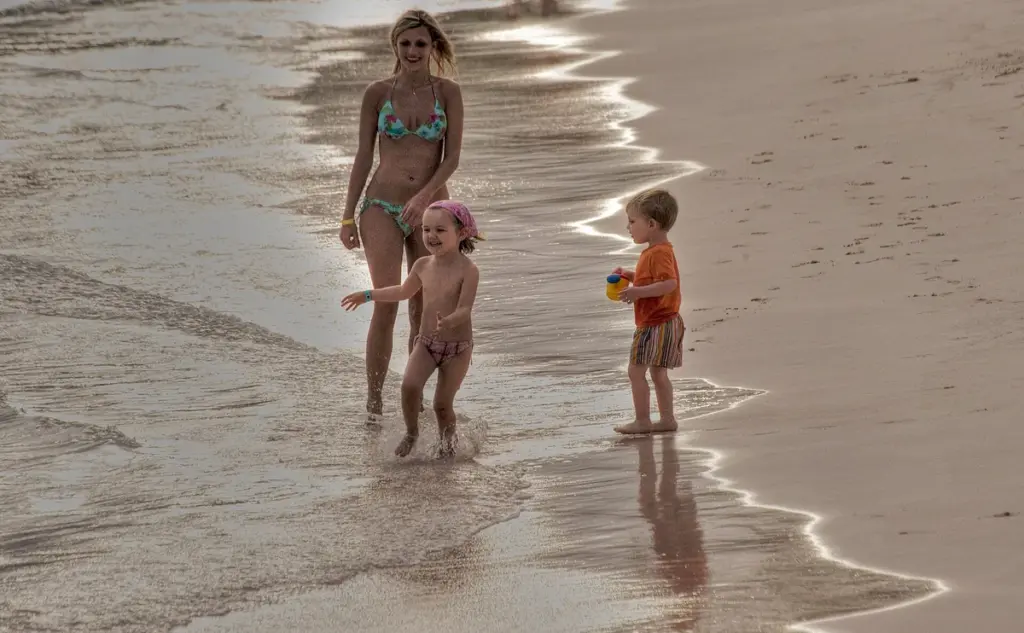 Madre con dos niños pequeños caminando por la orilla de una playa en Punta Cana