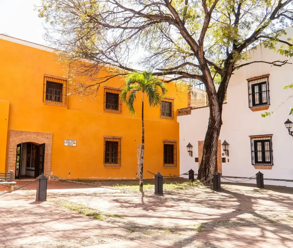 Edificio del antiguo convento dominico con muros color naranja y un árbol en la plaza