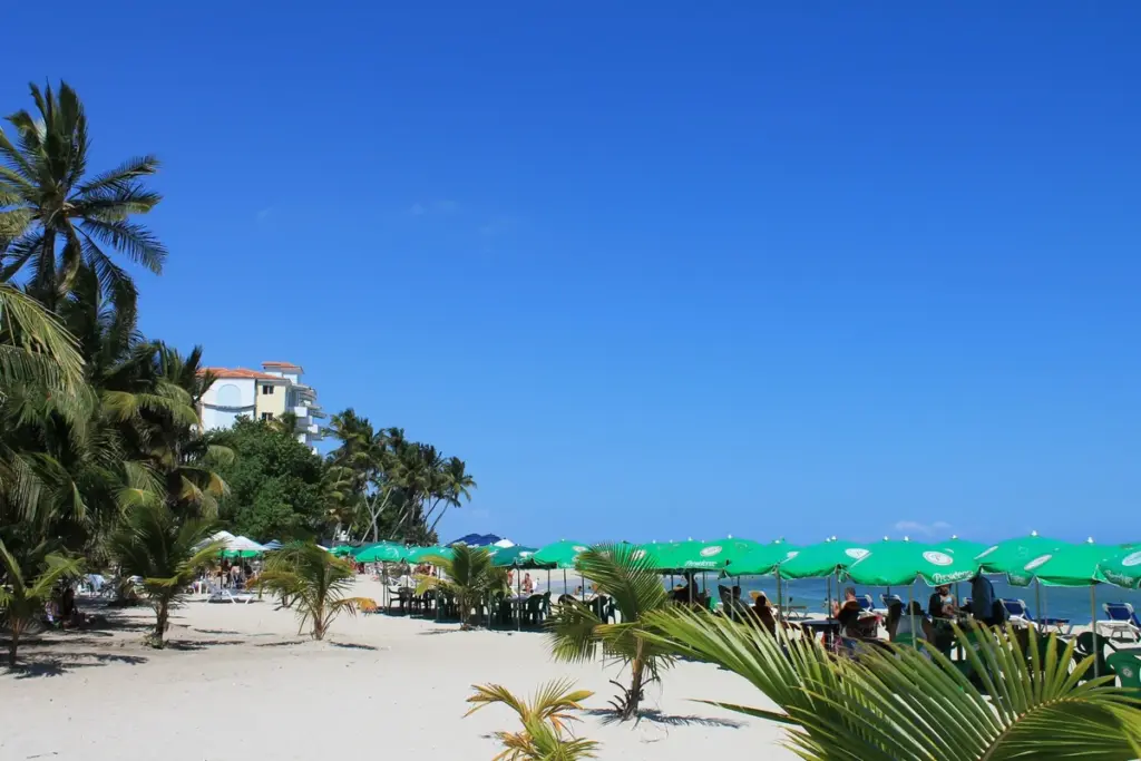 Orilla de la playa pública de Juan Dolio con agua turquesa y hoteles al fondo