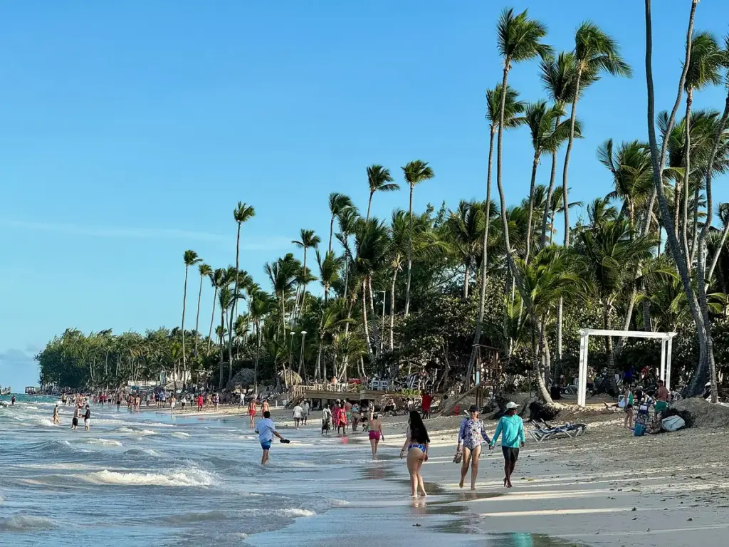 Palmeras y bañistas en la orilla de Playa Bávaro en un día soleado