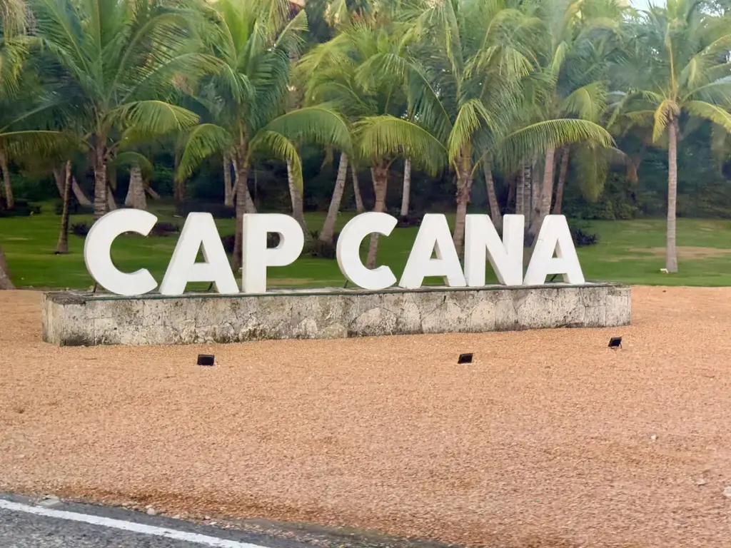 Letras gigantes de Cap Cana sobre un muro de piedra con palmeras al fondo