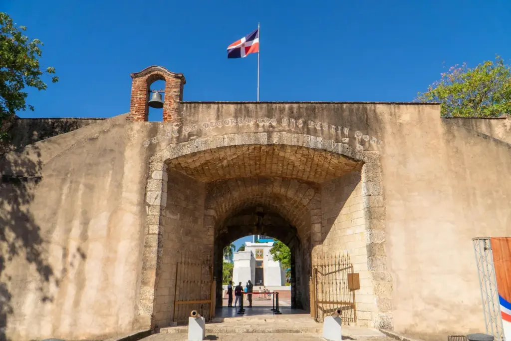 Arco de la Puerta del Conde visto de frente con el campanario y la bandera dominicana