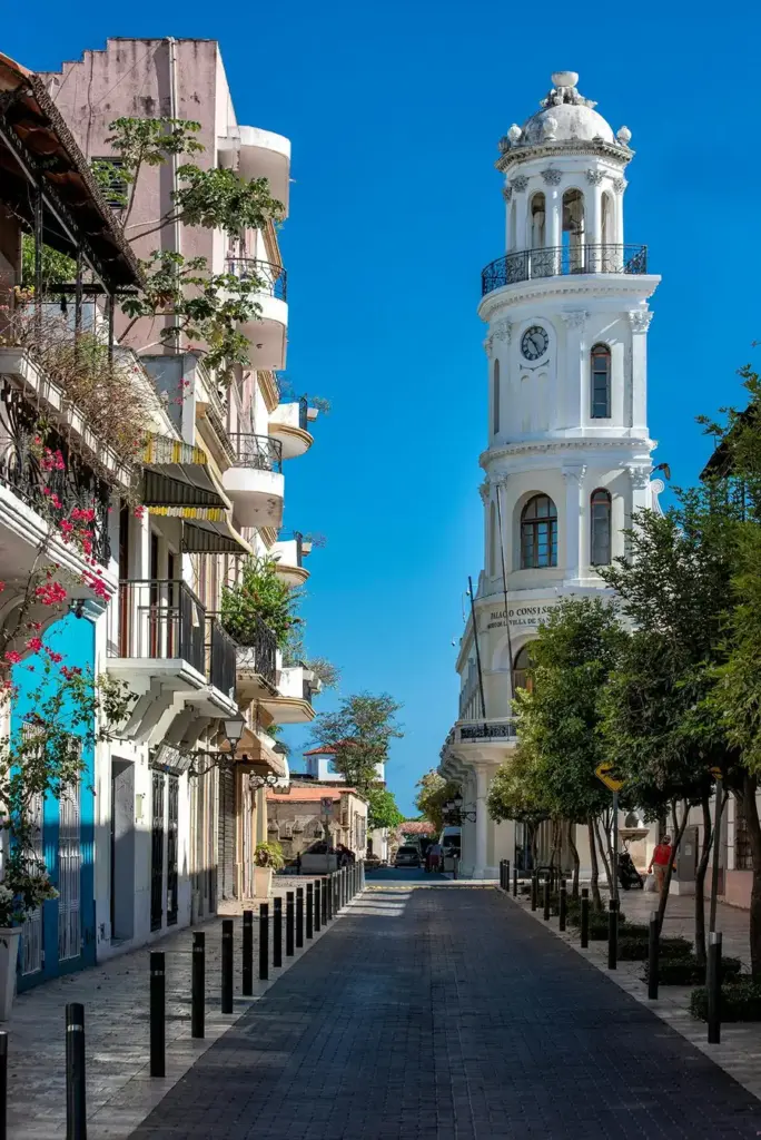 Calle de la Ciudad Colonial con casas de colores, balcones y un campanario blanco al fondo