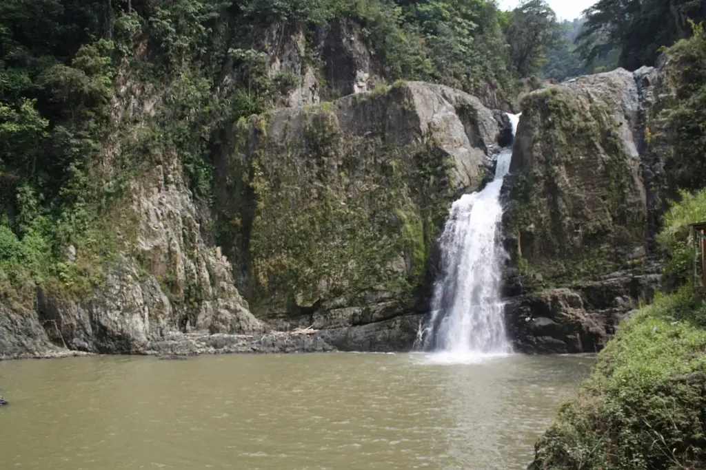 Salto de Jimenoa cayendo entre paredes de roca y vegetación en Jarabacoa