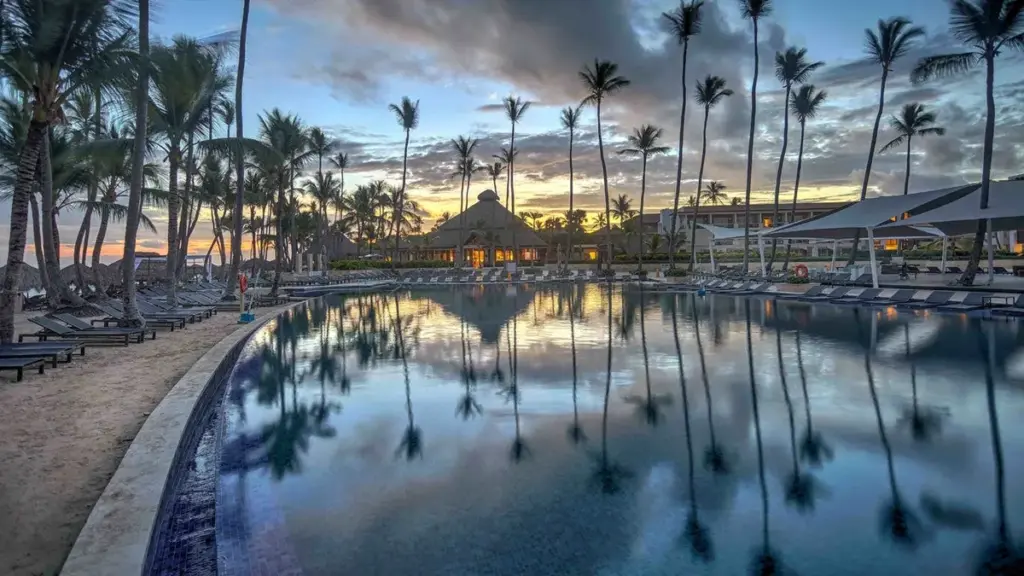 Piscina del Royalton Punta Cana al atardecer con palmeras reflejadas en el agua