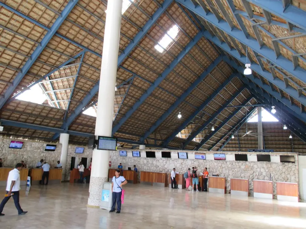 Interior del Aeropuerto Internacional de Punta Cana con techo de madera y mostradores