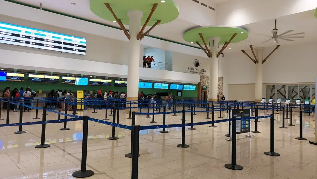 Área de chequeo del Aeropuerto Internacional de Punta Cana con filas y pantallas de vuelos
